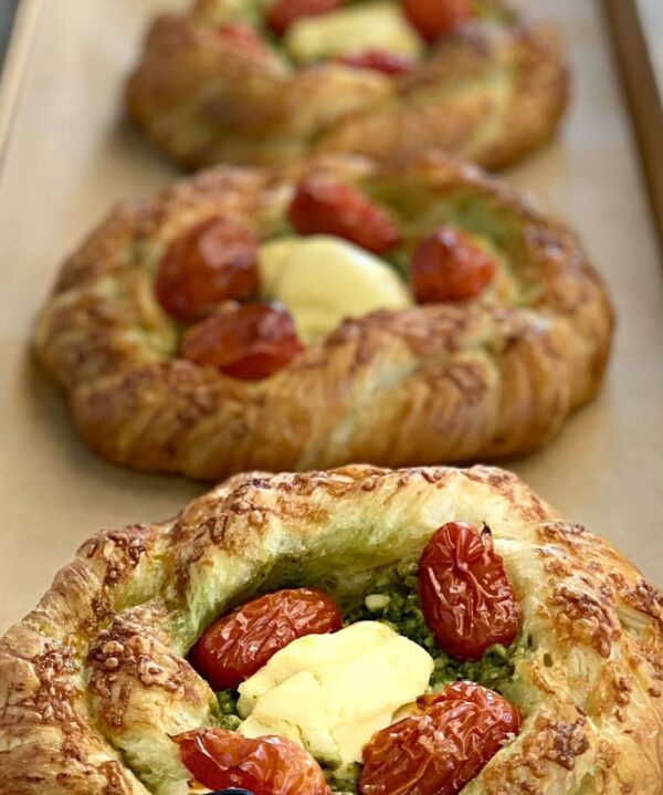 Three pastries with cheese and tomatoes on top of a pan.