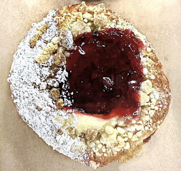 A close up of a pastry with powdered sugar and jam